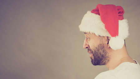 Bearded man wearing santa claus hat, side view on grey with copy space. Christmes time.の写真素材