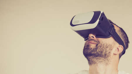 Adult short bearded guy exploring virtual reality wearing VR goggles being into technology.