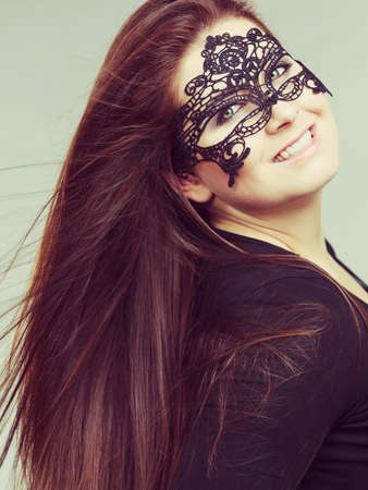 Happy pretty mysterious woman wearing black eye lace mask having long brown hair.の写真素材