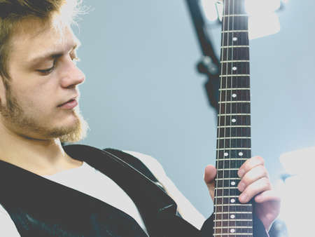 Teen hardcore man wearing metal outfit playing on electric guitar heavy rock music.