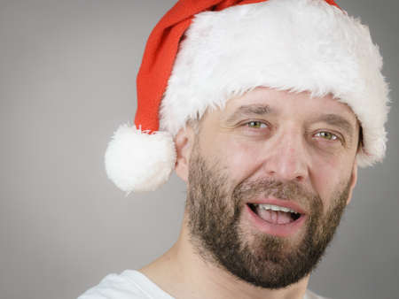 Bearded man wearing santa claus hat portrait, on grey. Christmes time.の写真素材
