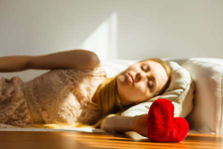 Sad lonely woman lying on bed being alone with heart shape.の写真素材