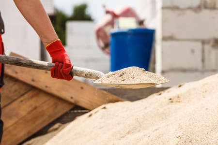 Unrecognizable person worker using shovel standing on industrial construction site, working hard on house renovation.の写真素材