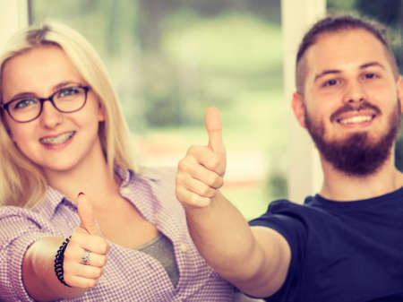Education, friendship, success and teenage concept. Two college students girl and boy giving thumb up gesture of approval an success with their handsの写真素材