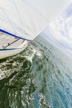Yachting on sail boat during sunny summer weather on calm blue sea water. Sporty transportation conept.の写真素材