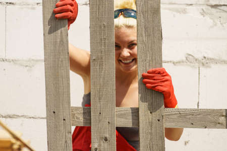 Woman about to do some work on construction site holding wooden Euro pallets