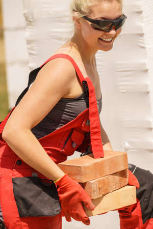 Strong pretty woman working on construction site, building house, installing bricks. Industrial work concept.の写真素材