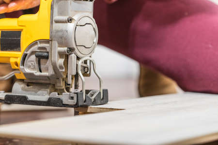 Person cutting floor panels using industrial tool to cut perfect shape for instalation. Home renovation concept.の写真素材