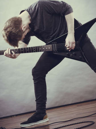 Man being passionate about his music hobby, playing electric guitar emotionally.の写真素材