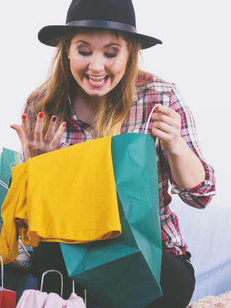 Happy funny joyful young woman in hat being positive after shopping on sales looking what she bought.の写真素材