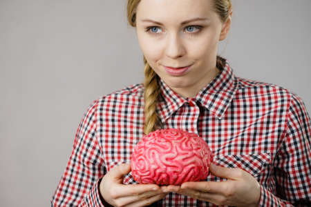 Intellectual expressions, being focused concept. Closeup of attractive woman happy thinking face expression holding brainの写真素材