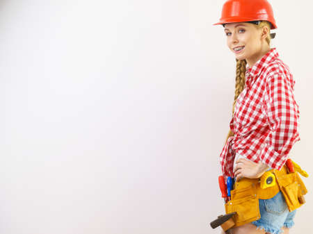 Happy joyful woman wearing helmet and checked shirt being positive about construction work.の写真素材