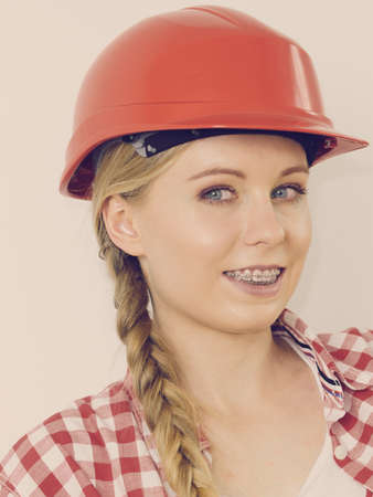 Happy joyful woman wearing helmet and checked shirt being positive about construction work.の写真素材