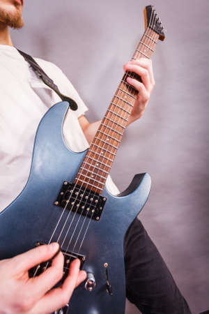 Close up of man playing on electric guitar during gig or at music studio. Musical instruments,...