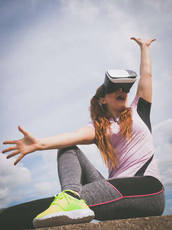 Young woman testing VR eyeglasses outside. Female wearing virtual reality headset during summer...