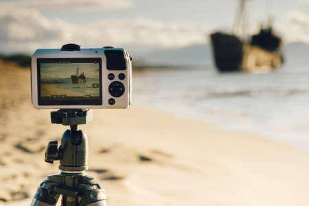 Professional camera on tripod taking picture film video from greek coastline with rusty shipwreck Dimitrios near Gytheio, Gythio Laconia Peloponnese Greece.の写真素材
