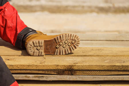 Unrecognizable person on construction site wearing protective worker red black pants trousers, sole close up.の写真素材