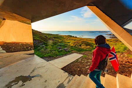 Tourist woman with norwegian flag enjoying sea coast view from Bukkekjerka rest stop area on Andoya...