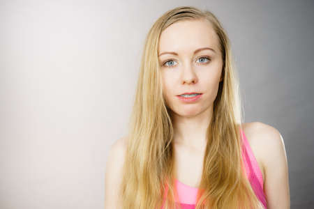 Portrait of young teenage blonde woman. Beauty of adolescence cocnept. Grey background.