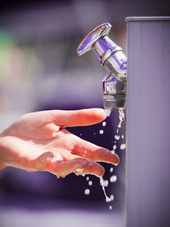 Woman cleaning washing her hands outdoor in marine water dispenser. Hygiene concept.