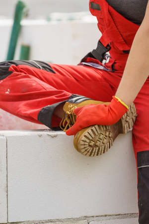 Unrecognizable person on construction site wearing protective worker red black pants trousers
