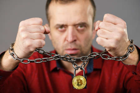 Man having problems with crypto currency. Adult guy being tied up with block chain bitcoin.