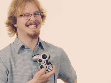 Nerd geek young adult man playing on the video console holding game pad. Gaming gamers concept.の写真素材