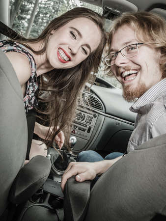 Happy man and woman during traveling trip. Couple, friends sitting inside vehicle car driving riding somewhere.の写真素材