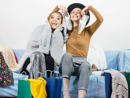 Two happy joyful women having fun after shopping, picking outfit in closet. Female friends fooling around.の写真素材