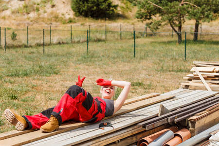 Woman in dungarees relaxing after hard work on construction site. Young female lying outdoor taking a breakの写真素材