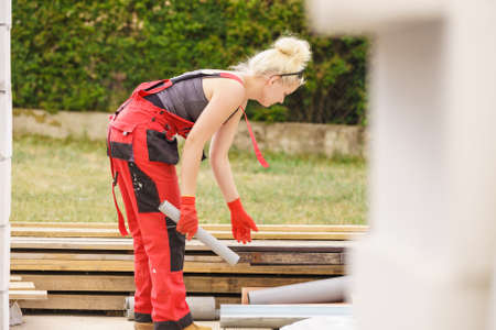 Blonde strong woman in dungarees working on home construction site. Women power, gender equality,...