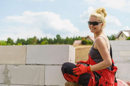 Woman in dungarees relaxing after hard work on construction site. Young female lying outdoor taking a breakの写真素材