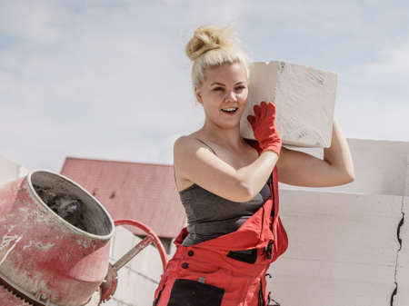 Strong pretty woman working on construction site, building house, installing gray airbricks. Industrial work concept.の写真素材