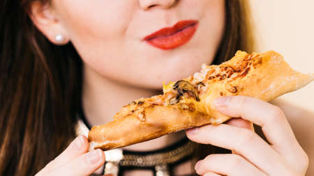 Young woman eating hot fresh pizza slice. Delicious fast food meal. People, italian cuisine concept.の写真素材