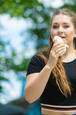 Happy funny young woman with long brown hair eating ice cream having fun.の写真素材