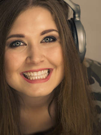 Cheerful teenage woman listening to music through big headphones having fun. Crazy girl