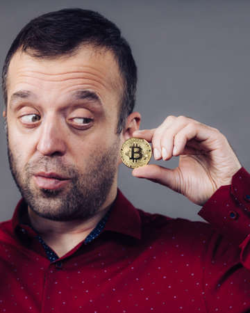 Man holding golden bitcoin coin sign, digital symbol of new virtual currencyの写真素材