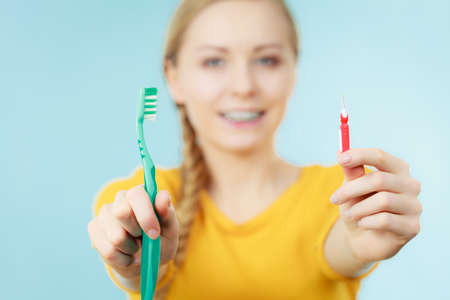 Dentist and orthodontist concept. Young woman with blue braces cleaning and brushing teeth using two...