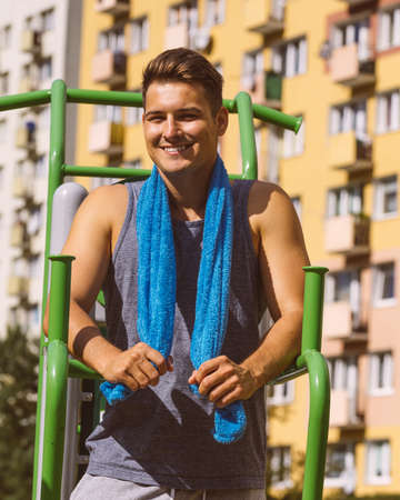 Young handsome man working out in outdoor gym, public park. Sporty guy about to exercise on machine....