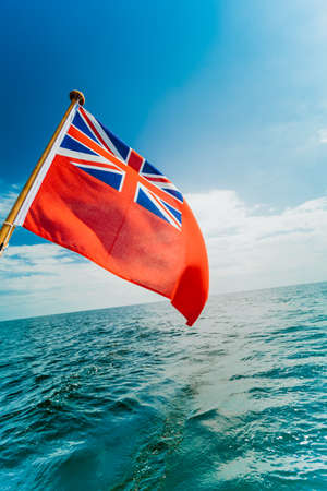The UK red ensign the British maritime flag flown from yacht sail boat, blue sky and Baltic sea....