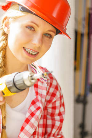 Young woman using drill to fix or installing windows. Girl working at flat remodeling. Building, repair and renovation.の写真素材