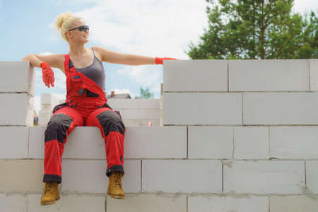 Woman in dungarees relaxing after hard work on construction site. Young female lying outdoor taking a breakの写真素材