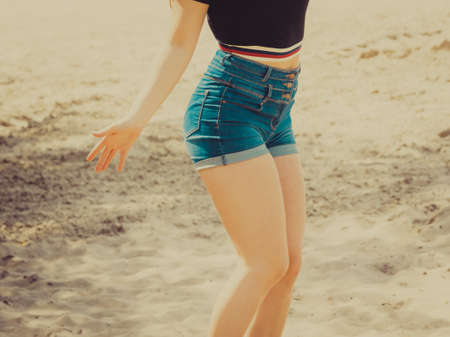 Woman showing her sexy curves. Hips and legs body part in short denim shorts.