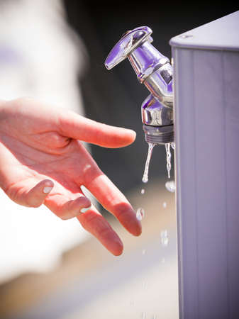 Woman cleaning washing her hands outdoor in marine water dispenser. Hygiene concept.の写真素材