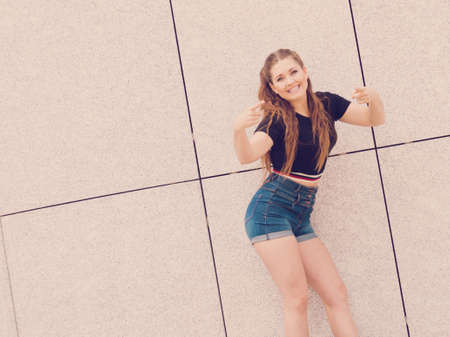 Young teenage woman wearing denim shorts and black crop top. Female presenting fashionable summer outfit.の写真素材