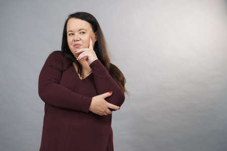 Thinking adult woman, plus size female gesturing with hands seeking for solution, having...