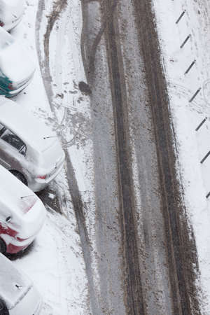 Transportation, winter season and seasonal specific. Parked cars covered in snow after blizzard and urban road street, top viewの写真素材