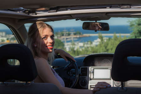 Young driver, pretty blonde woman behind steering wheel. Female riding using car, traveling, going...