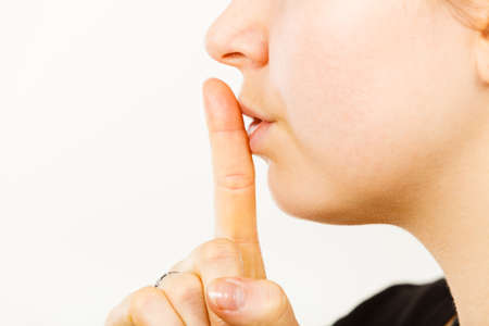 Woman showing silence shh gesture with finger close to mouth asking for being quietの写真素材