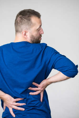 View from back on man having terrible loins pain ache. Guy suffering from health problem.の写真素材